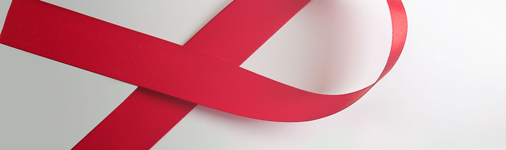 Ruban rouge formant une boucle sur fond blanc, symbolisant la sensibilisation au VIH/SIDA.