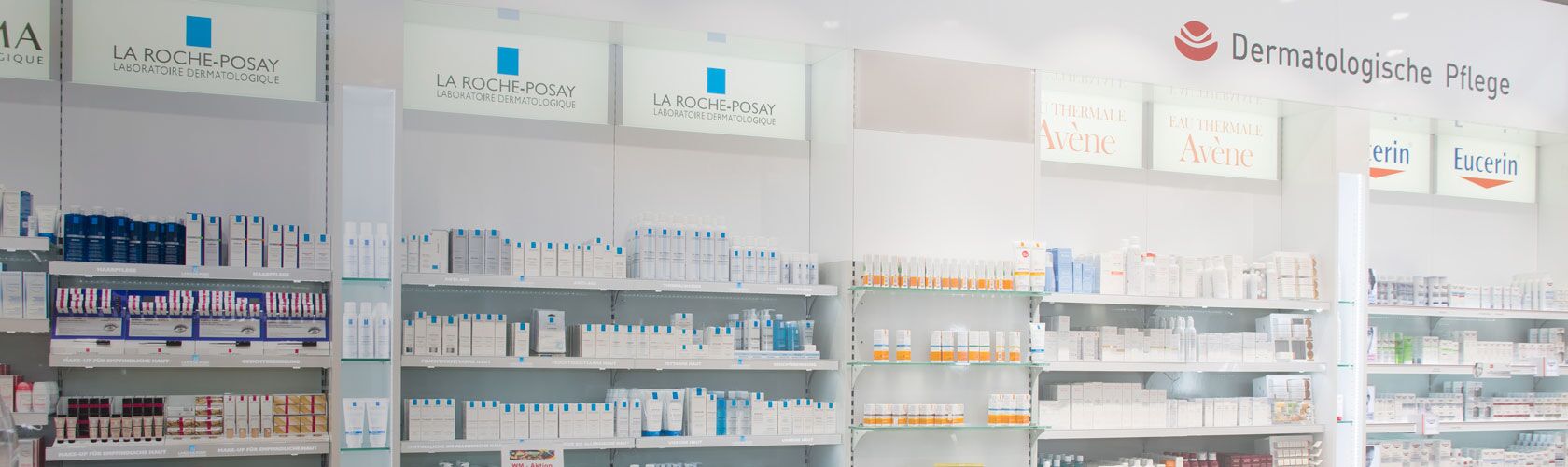 Regale voller Dermokosmetikprodukte von Marken wie La Roche-Posay und Avène in einer Apotheke unter dem Schild "Dermatologische Pflege".