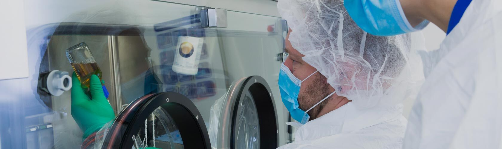 Des techniciens en blouse blanche travaillent dans un laboratoire de cytologie spécialisé en oncologie, manipulant des échantillons.