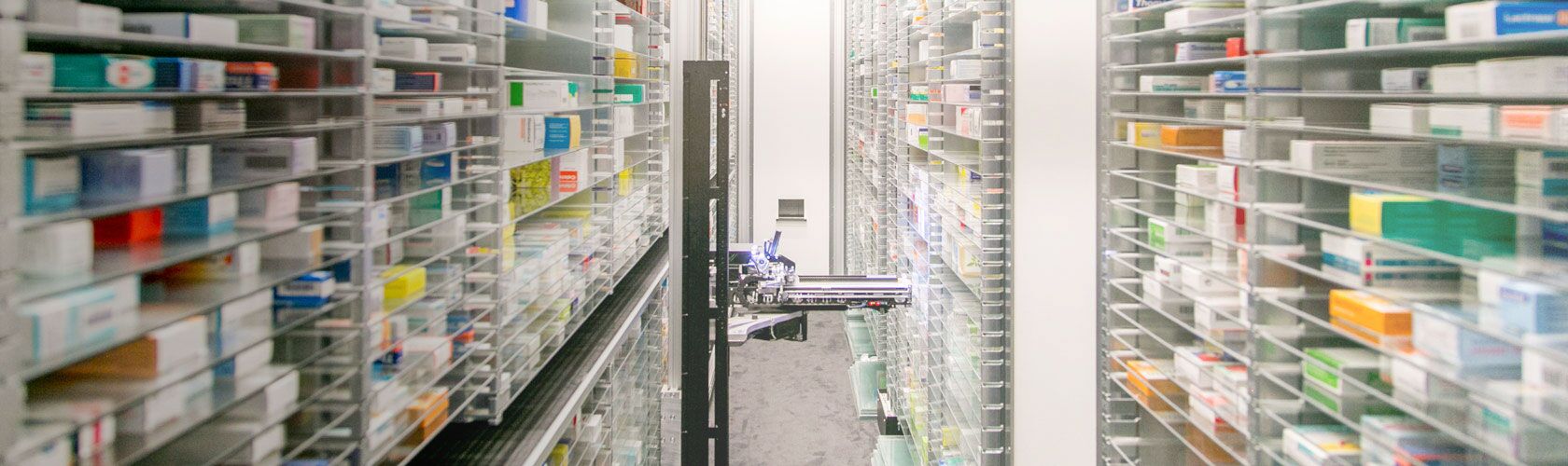 Allée étroite d'une pharmacie moderne avec des étagères remplies de boîtes de médicaments organisées avec précision.